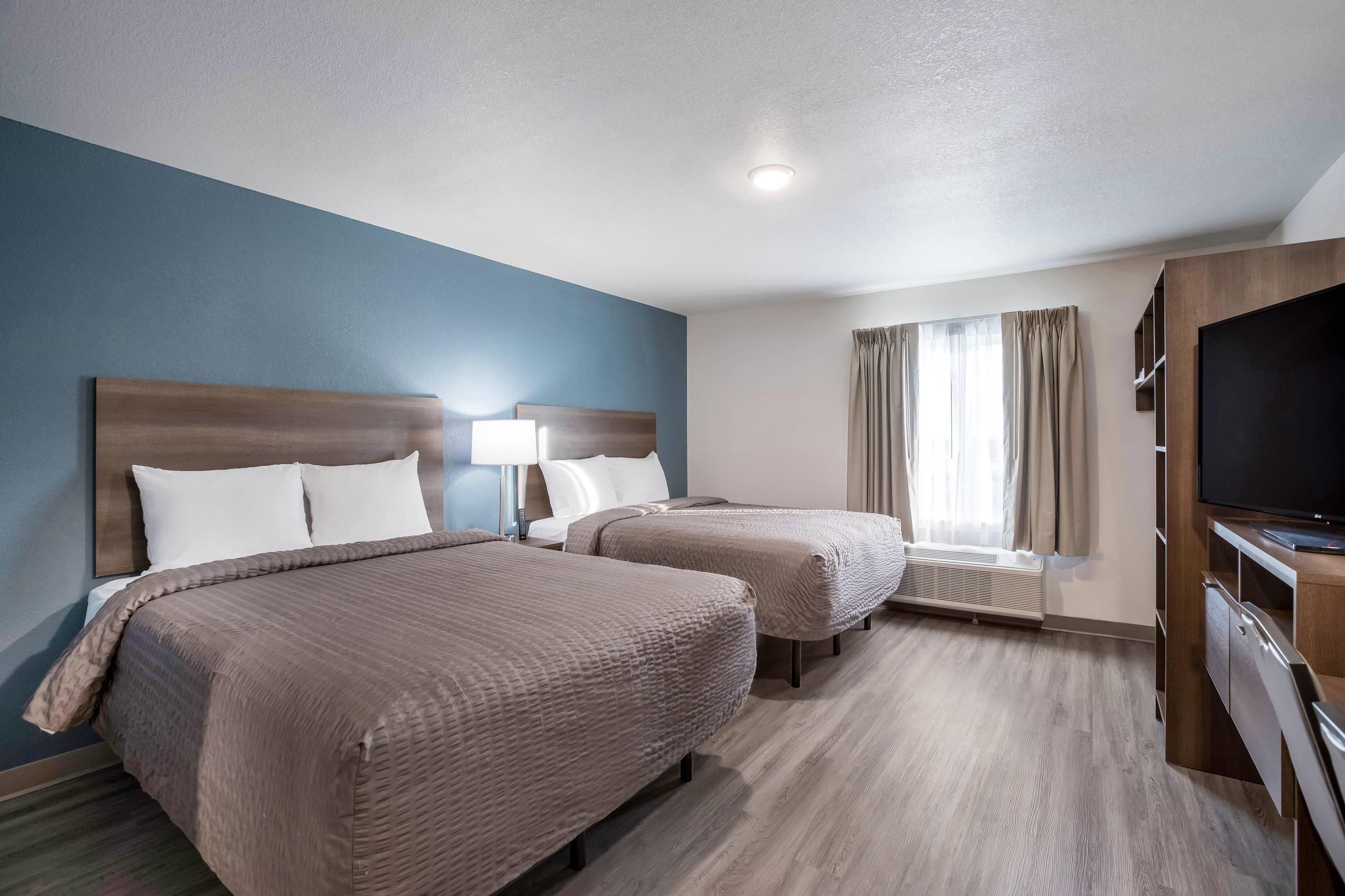 A hotel room with two beds, a TV, and a window with curtains.
