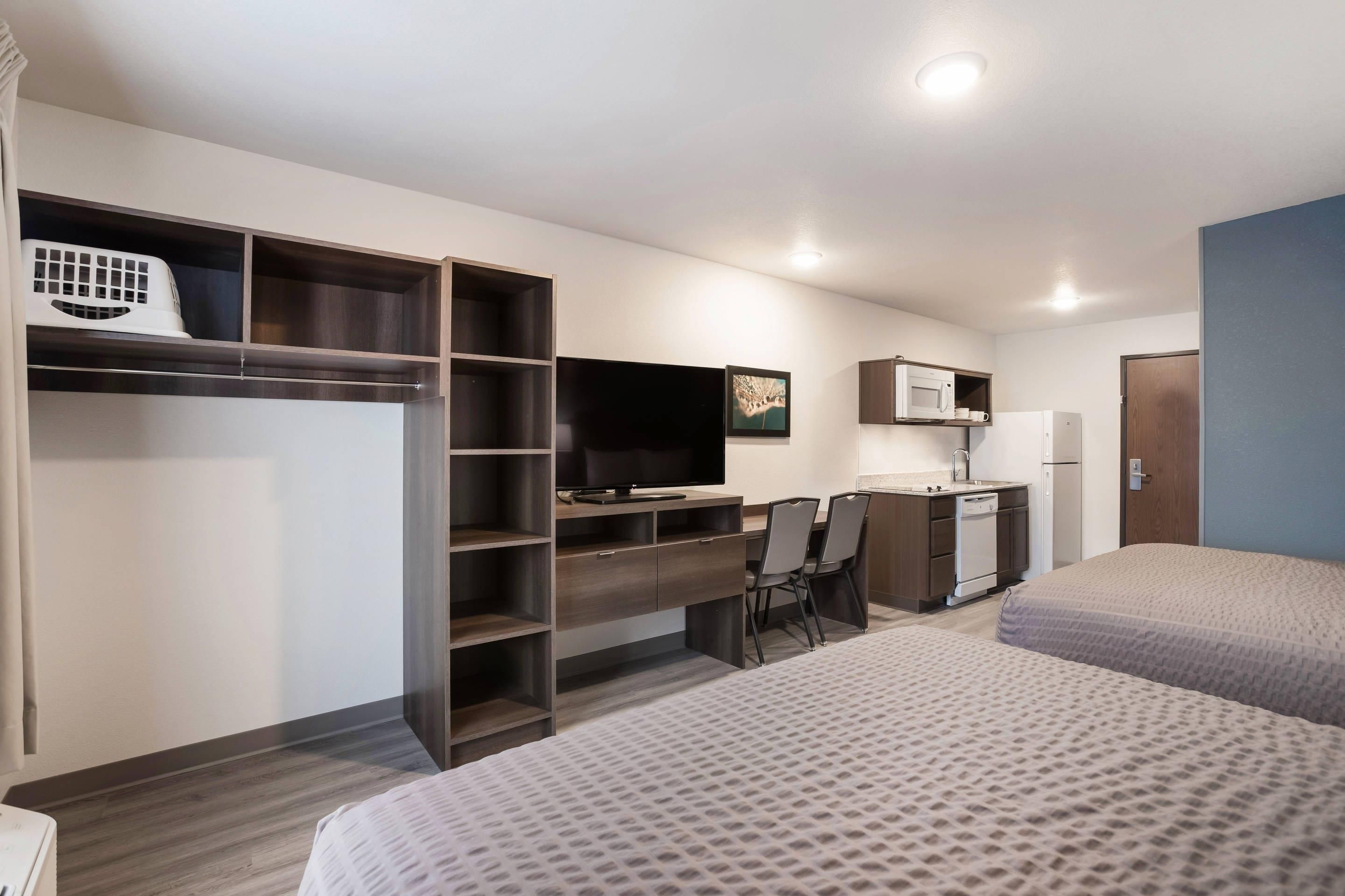 A compact hotel room with a bed, a desk, a television, a microwave, and a refrigerator.