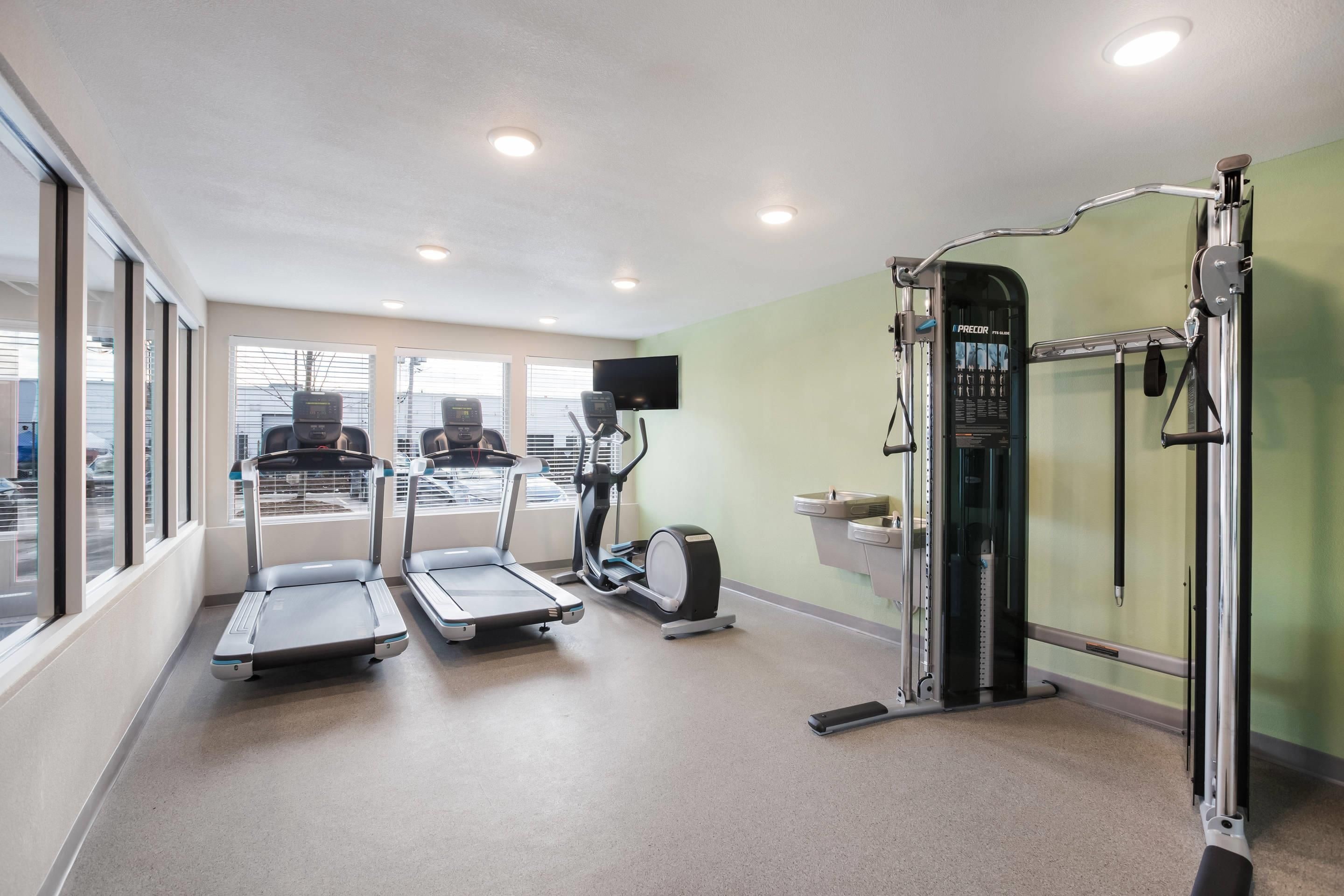 Une salle de remise en forme équipée de tapis de course, d’un vélo d’appartement et d’une machine de musculation.