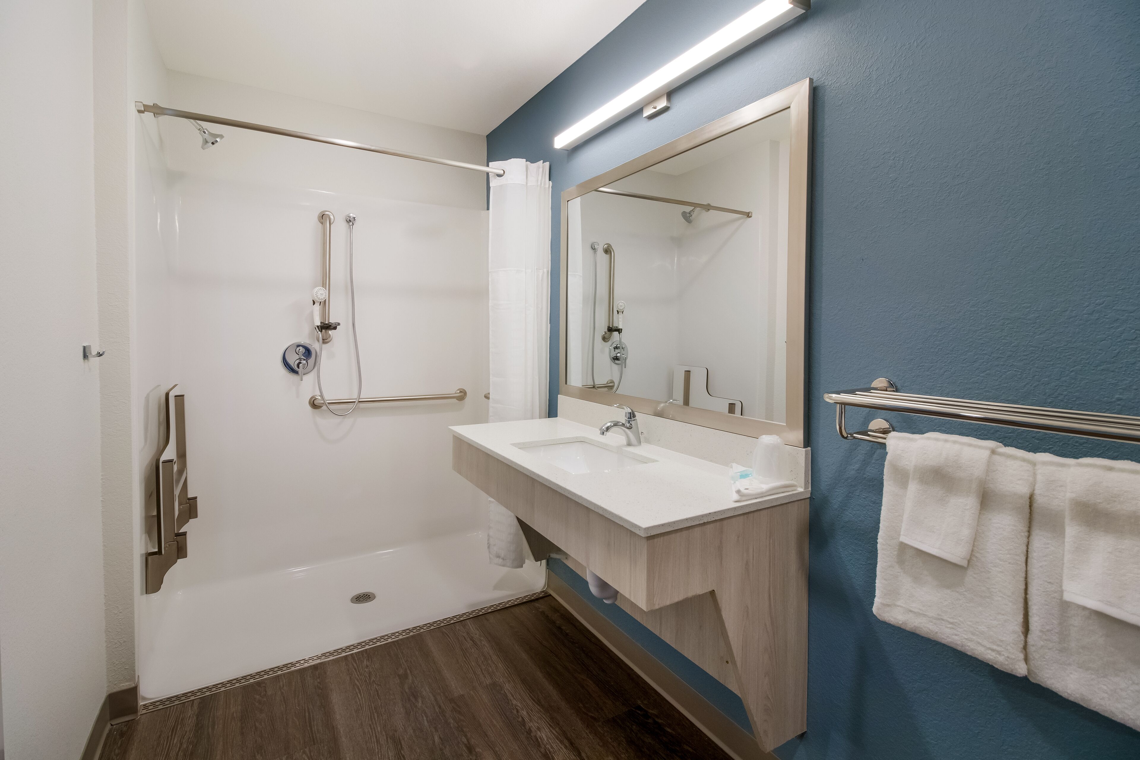 A modern bathroom with a walk-in shower, a sink with a mirror, and a towel rack.