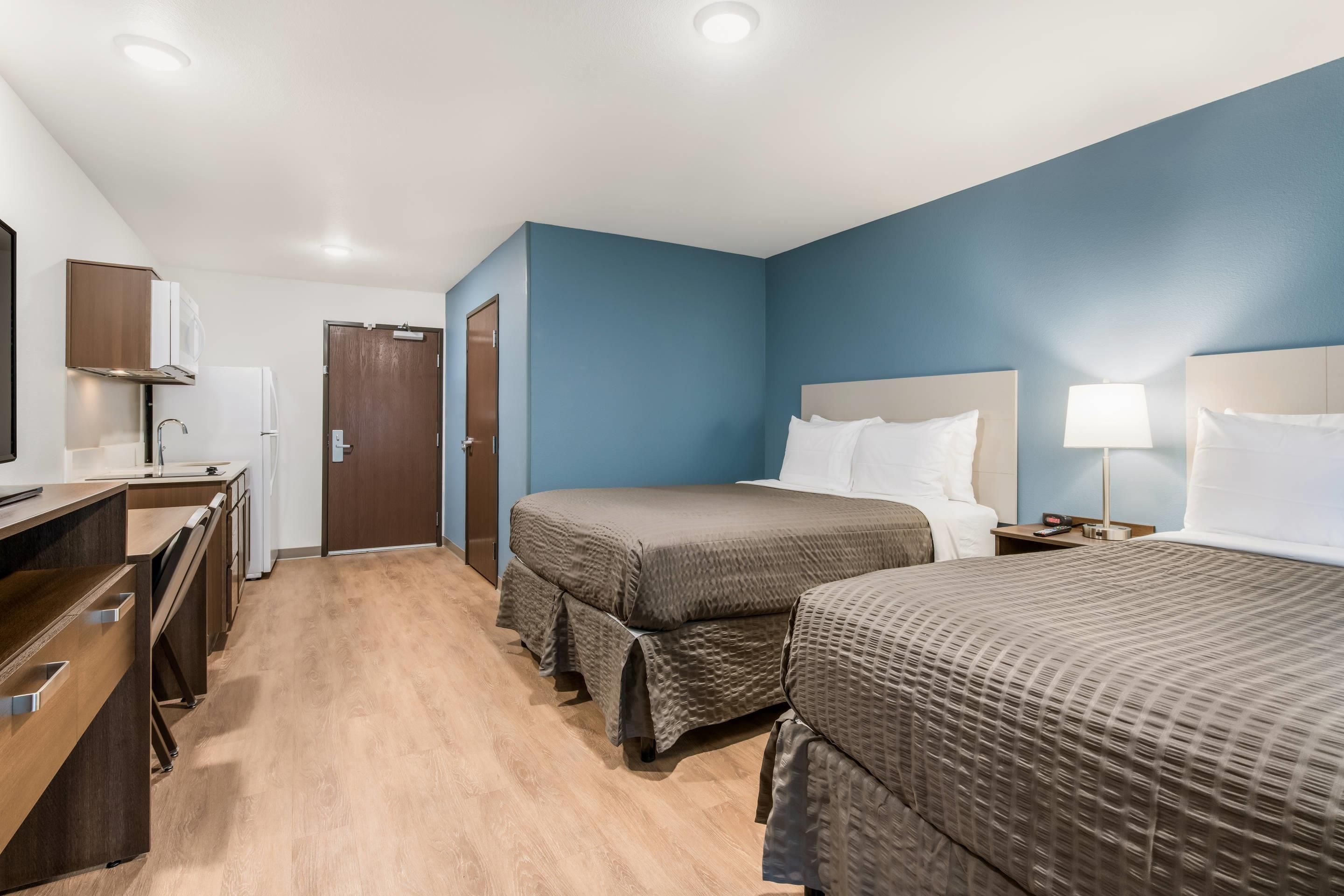 A hotel room with two beds, a desk, and a wardrobe.
