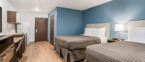 A hotel room with two beds, a desk, and a wardrobe.