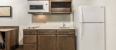 A compact kitchen with a microwave, a sink, and a refrigerator.