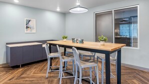 Un comedor moderno con una mesa de madera, sillas de metal, un armario gris y una lámpara colgante.