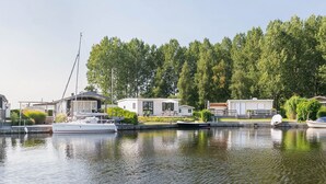 A lakeside property with a dock, a boat, and several mobile homes. - Picturesque holiday home with garden on open waters (Terherne)