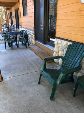Un patio couvert doté d’un mur en pierre, d ’une terrasse en bois et d’un espace salon extérieur comprenant une table et des chaises.