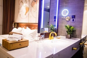 A modern hotel room with a large bed, a vanity with a mirror, a sink, and a small potted plant. - James Joyce Coffetel Shanghai Hongqiao Hub National Convention and Exhibition Center (Shanghai)
