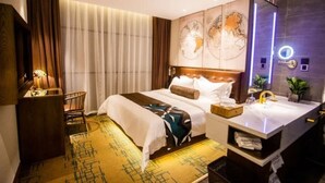 Ein Hotelzimmer mit einem großen Bett, einem Schreibtisch mit Lampe, einem Schminktisch mit Spiegel und einer Karte an der Wand.