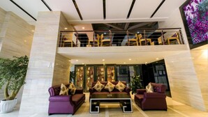 A modern lobby with a high ceiling, a double-height seating area, and a large screen displaying an image of flowers. - Lavande Hotel Chengdu Shuangliu International Airport (Chengdu)