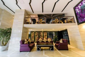A modern lobby with a high ceiling, a double-height seating area, and a large screen displaying an image of flowers. - Lavande Hotel Chengdu Shuangliu International Airport (Chengdu)