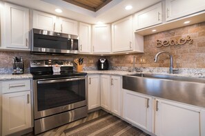 Una cocina moderna con electrodomésticos de acero inoxidable, armarios blancos y una pared de ladrillo decorativa.