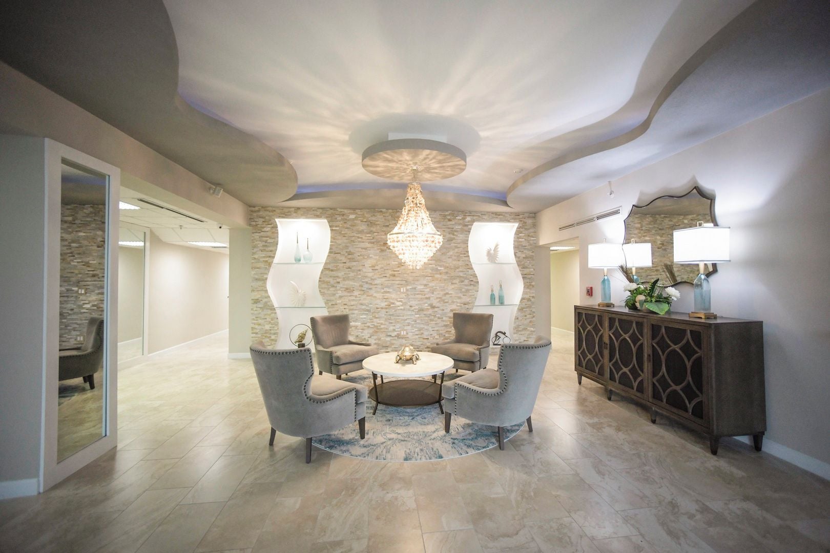 Ein modernes Interieur mit einem runden Tisch, vier Stühlen, einer dekorativen Chandelier und einer Steinwand.