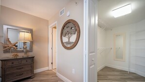 A hallway with a wooden dresser, a mirror, and a wall-mounted tree decoration. - Gorgeous 3/3 Oceanfront at Seychelles -- Unit 504 (Daytona Beach Shores)