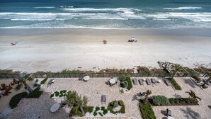 A beach view with a patio area featuring lounge chairs and tables, overlooking the ocean. - Gorgeous 3/3 Oceanfront at Seychelles -- Unit 504 (Daytona Beach Shores)