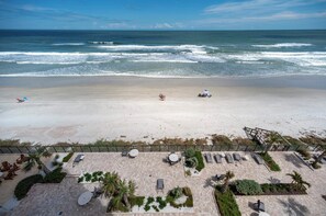 A beach view with a patio area featuring lounge chairs and tables, overlooking the ocean. - Gorgeous 3/3 Oceanfront at Seychelles -- Unit 504 (Daytona Beach Shores)