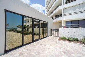 A modern building with a fitness room, large glass doors, and a paved walkway.