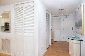Ein Flur mit weißen Türen, einem Konsolentisch mit Glasplatte und einem Bild an der Wand.