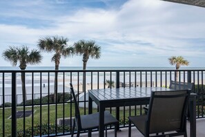 Ein Balkon mit Tisch und Stühlen mit Blick auf einen Strand.