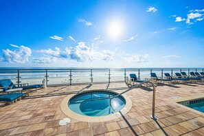Zona de piscina con sillas de descanso y vista a la playa.
