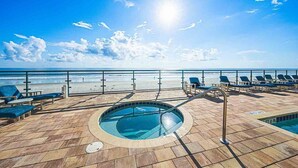 Un espace piscine avec des chaises longues et vue sur la plage.