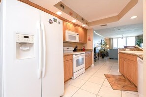 Une cuisine moderne avec des appareils électroménagers blancs, des armoires en bois et un sol carrelé.