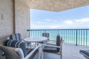 Un balcon avec vue sur l’océan, aménagé avec une table ronde et des chaises à rayures.