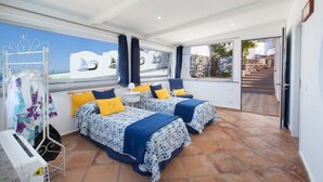Un dormitorio con dos camas, una ventana con vistas a veleros y un balcón con un muro de piedra.