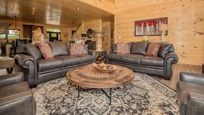A spacious living room with a large wooden ceiling, two leather sofas with patterned cushions, a round coffee table, and a patterned rug. - 11 Miles to Gatlinburg! Indoor Heated Pool/Theater Room/Hot Tub/ DISCOUNTS! (Sevierville)