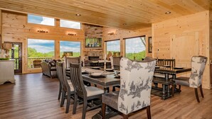 A wooden cabin interior with a dining area, large windows, and a stone fireplace. - 11 Miles to Gatlinburg! Indoor Heated Pool/Theater Room/Hot Tub/ DISCOUNTS! (Sevierville)