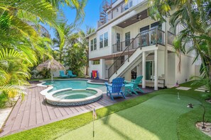 A two-story house with a swimming pool, outdoor seating, and a well-maintained lawn. - EV Charger, Portside Paradise by SeaBreeze Vacation (Holmes Beach)