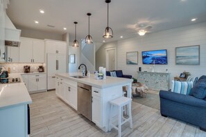 A modern kitchen with white cabinetry, a central island, and pendant lighting. - Portside Paradise (Holmes Beach)