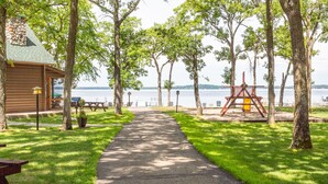 A pathway leading to a cabin with a view of a lake.