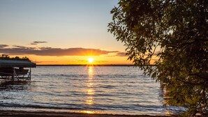 Een strand met een houten constructie, rustig water en een zonsondergang.