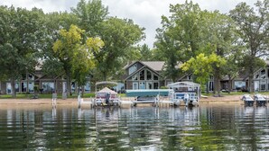 Una propiedad junto al lago con barcos amarrados, un embarcadero techado y varias cabañas con grandes ventanales.
