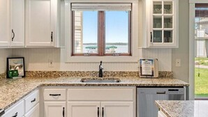 A kitchen with white cabinets, a granite countertop, a window with a view, and a built-in dishwasher. - Lakeside Comfort in the Heart of Gull Lake, Beach Access, Boat Rentals (Nisswa)