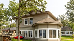 A two-story house with a bay window, a covered deck, and a red kayak. - Gull Lake at Your Doorstep |Waterfront Rental | Sleep 8 (Nisswa)