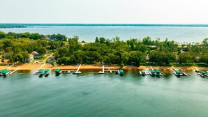 Une propriété au bord du lac, avec des bateaux amarrés, une plage de sable et une zone boisée.
