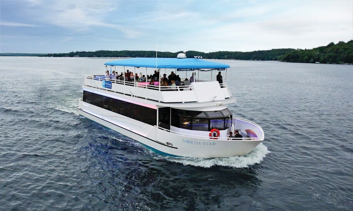 Un barco grande de varios niveles con toldo azul, identificado como "North Star", navegando sobre un cuerpo de agua.