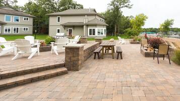 Un patio con mobiliario exterior, una chimenea de piedra y vistas a un lago.