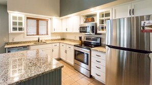Una cocina moderna con armarios blancos, electrodomésticos de acero inoxidable y encimera de granito.