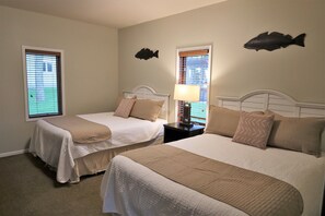 A hotel room with two beds, a nightstand with a lamp, and fish wall art.