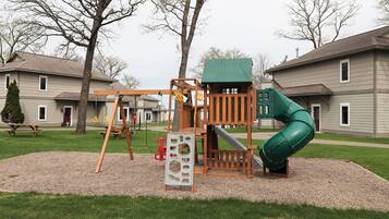Children can play on the swing set, slide, and climbing structure in this playground area.