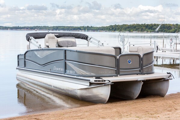A pontoon boat with a covered seating area, a cabin, and a flatbed.