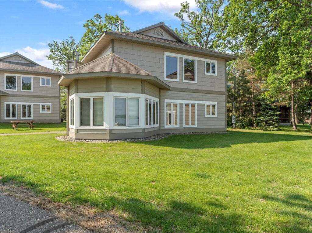 A two-story house with a large bay window, a covered patio, and a well-maintained lawn.