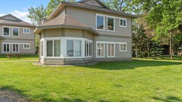 A two-story house with a large bay window, a covered patio, and a well-maintained lawn.