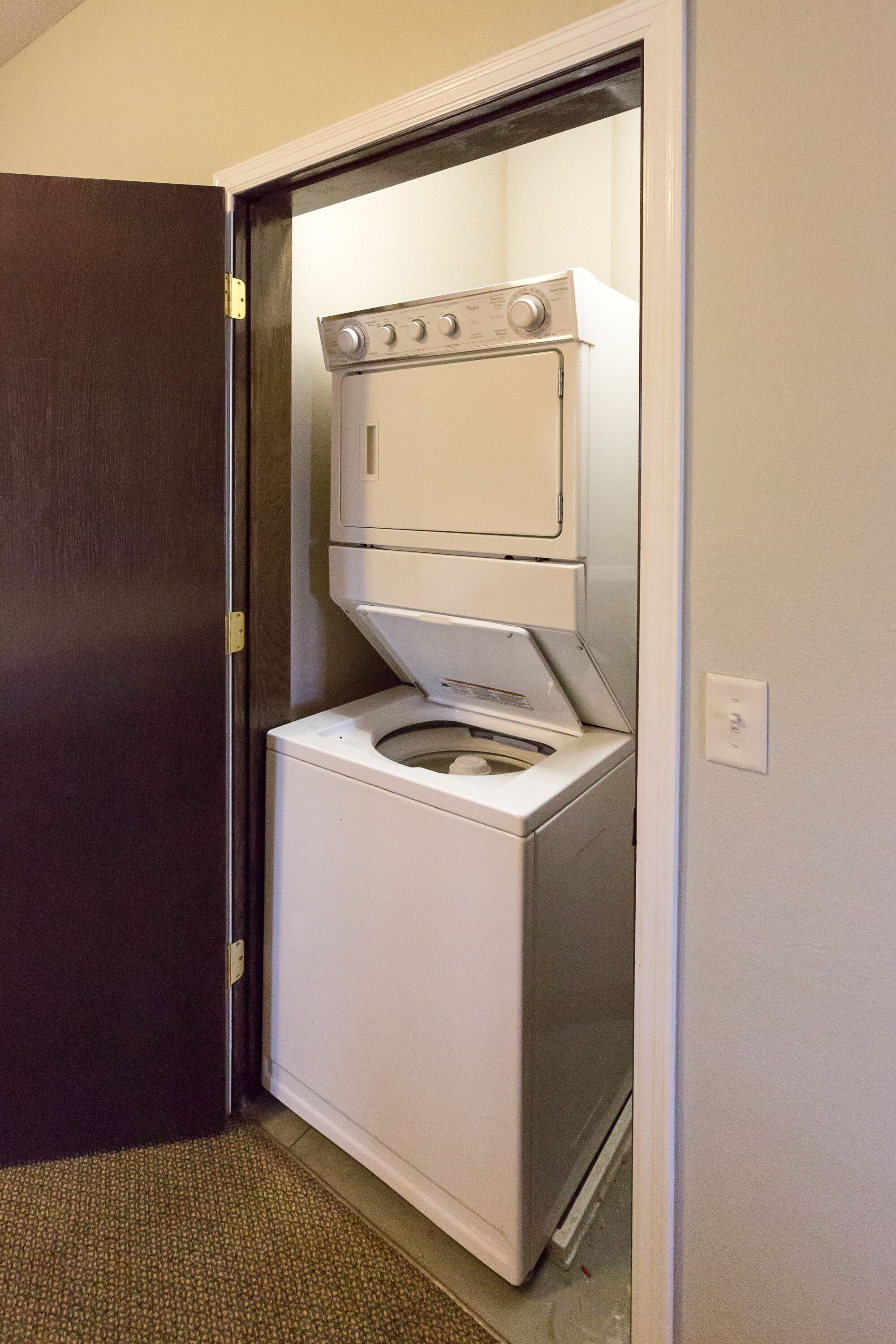 Une buanderie avec une machine à laver et un sèche-linge superposés dans un coin.