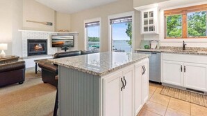 A spacious kitchen with a large island, white cabinetry, and a view of the outdoors.