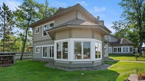 A two-story house with a large bay window, a stone retaining wall, and a well-maintained lawn.