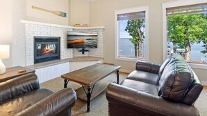 A living room with a fireplace, leather sofa, and a view of the outdoors.