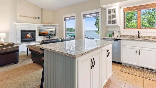 A spacious kitchen with a large island, white cabinetry, and a view of the outdoors. - Front Row Seat to Gull Lake Beach | Waterfront Condo (Nisswa)